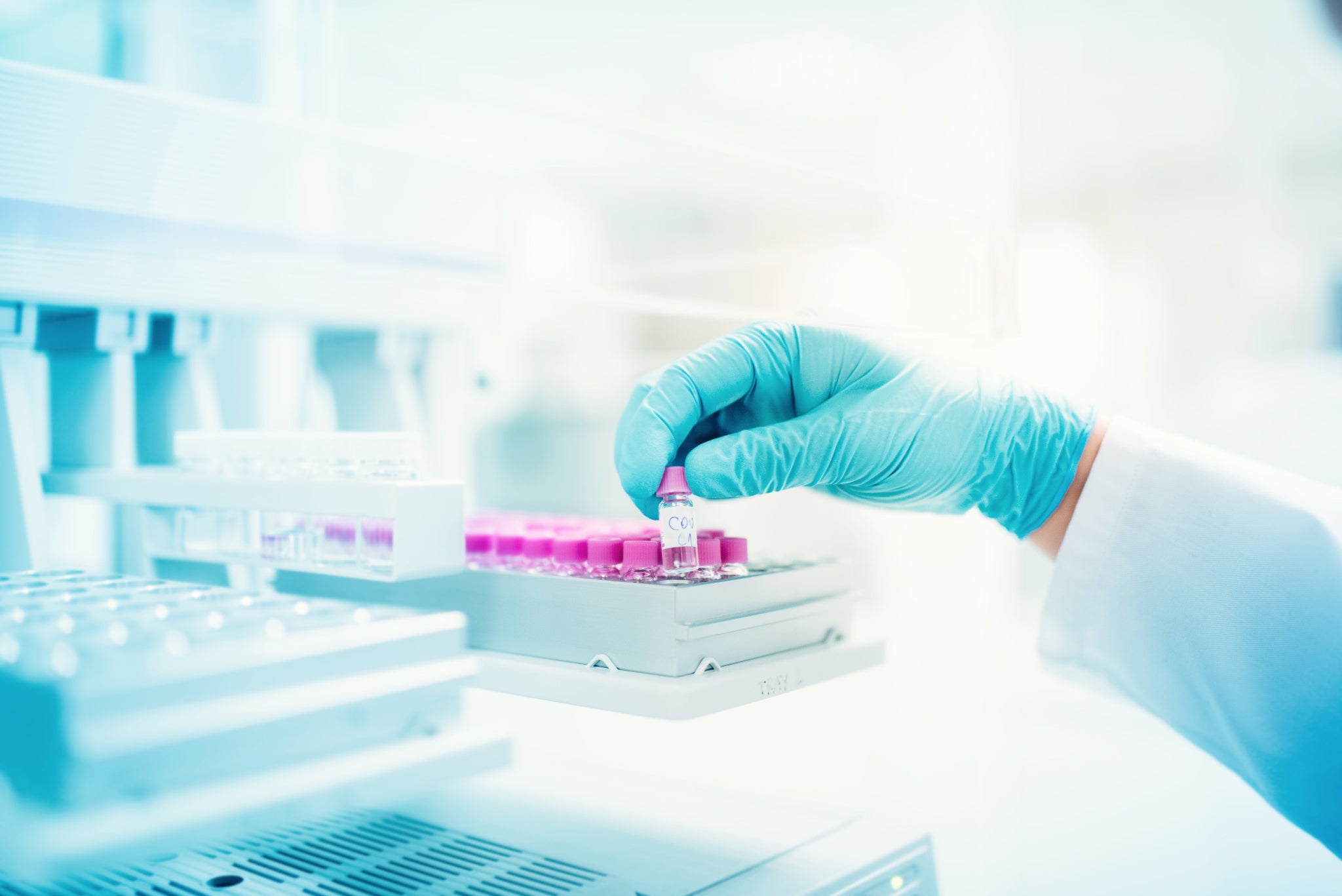 Person in a lab setting holding test tubes with a focus on safety and precision.