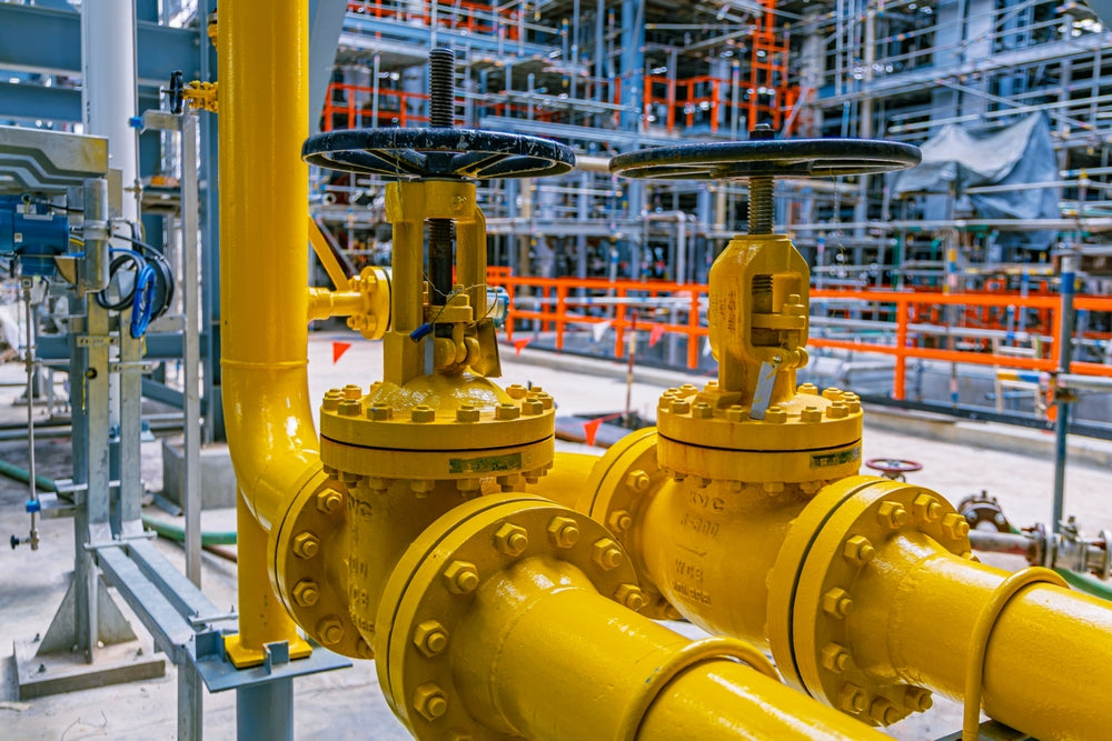 Yellow industrial valve with a complex background of pipes and structures